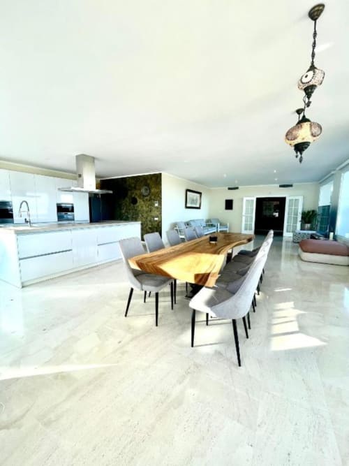 Zona de comedor de villa moderna con mesa de madera, cocina y vistas al océano en Málaga, España