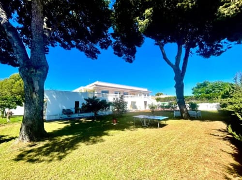 Villa Magos Málaga: Villa blanca con jardines impecables, terraza sombreada, piscina y vistas a las montañas bajo cielo despejado