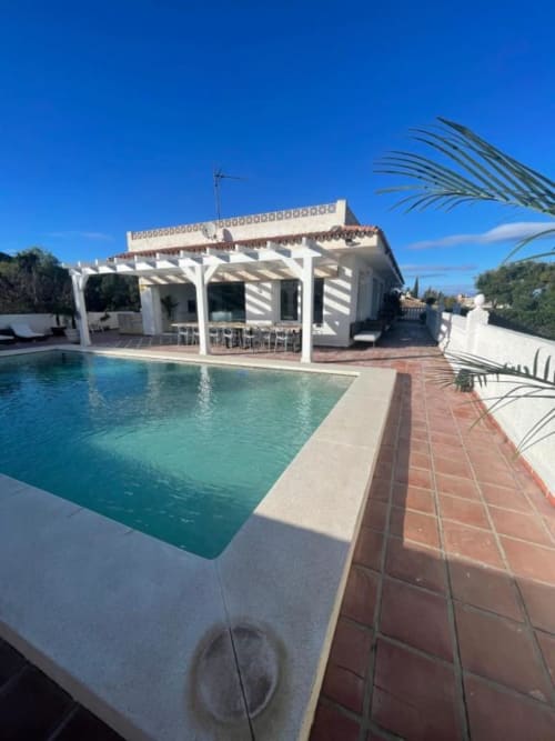 Piscina privada de Villa Magos con pérgola blanca, terraza y villa blanca en Málaga, España