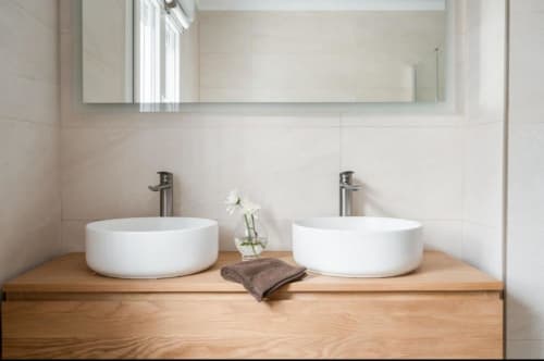 Baño moderno de la villa VILLA MAGOS en Málaga con dos lavabos blancos sobre tocador de madera