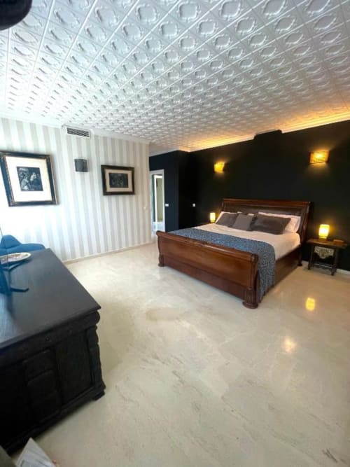 Dormitorio de lujo en VILLA MAGOS, Málaga con cama de madera, pared oscura, techo texturizado y equipamiento moderno