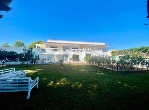 Villa Magos Málaga: villa encalada con terraza, jardín cuidado, tumbonas, vistas a la montaña y cielo azul
