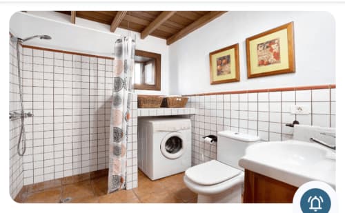 Cuarto de baño moderno con azulejos blancos, ducha, inodoro, lavabo y lavadora en villa Casa Rural La Caldera,