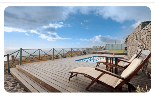 Terraza de madera con tumbonas con vistas a la piscina y al mar en la villa rural La Palma de Fuencaliente, España