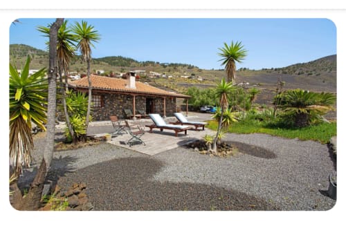 Villa Casa Rural Los Llanos Negros con patio de piedra, tumbonas, palmeras y vistas a montaña volcánica en Fuencaliente La