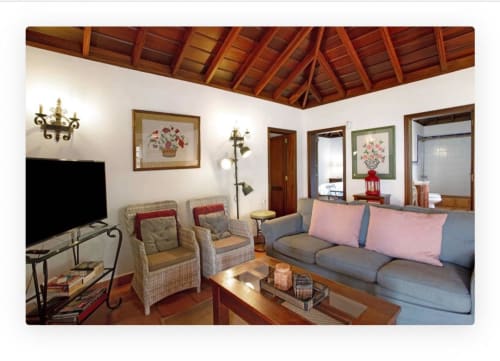Amplia sala de estar en villa de La Palma con sofá gris, sillones, techo de madera, TV y vistas al mar