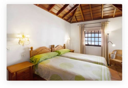 Luminoso dormitorio con techo de vigas de madera, ropa de cama verde y vistas al mar en la villa Casa Rural Los Llanos Negros en La Palma.