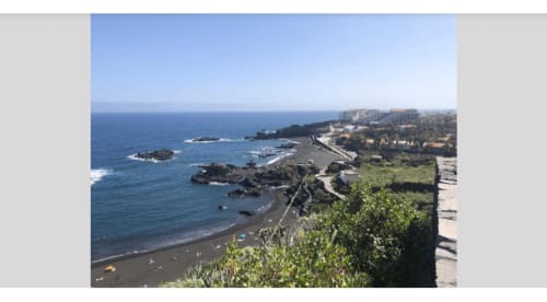 Vista costera de la playa Los Cancajos con arena negra, calas rocosas y edificios en la ladera de La Palma