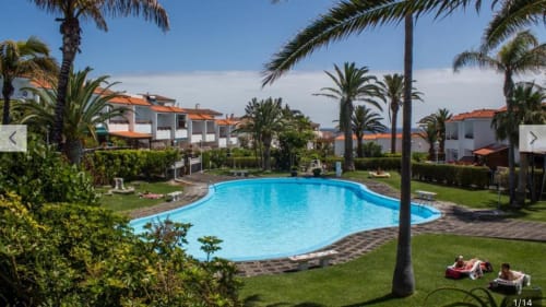 Piscina del resort con palmeras, huéspedes descansando y edificios blancos en La Palma entre viñas y Teneguía