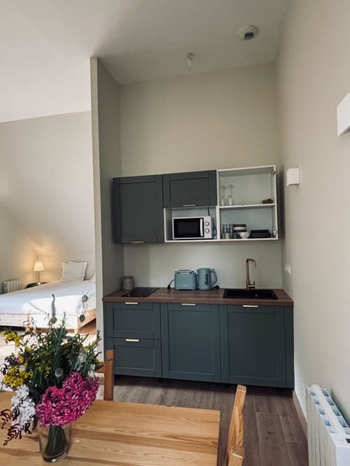 Kitchenette moderne avec armoires foncées et plan de travail en bois au Manoir De Daubeuf Grand Studio à Daubeuf-Serville