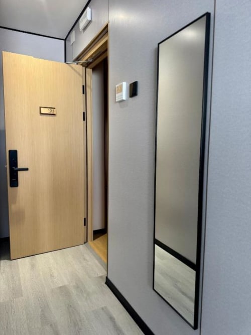 Pasillo moderno del ITOUR Hotel con puerta de madera clara hacia la habitación 108, espejo y diseño minimalista impecable en Museros