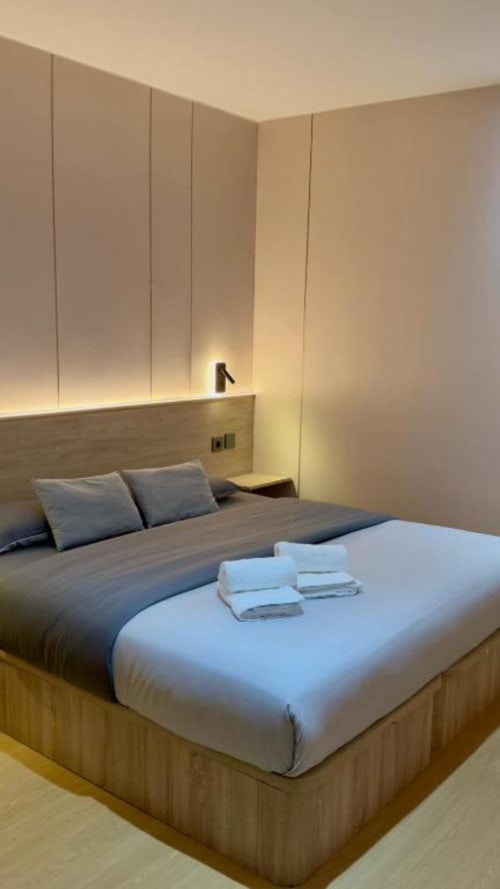 Moderna habitación doble en ITOUR Hotel & Coffee de Museros con iluminación cálida, diseño minimalista y ropa de cama blanca