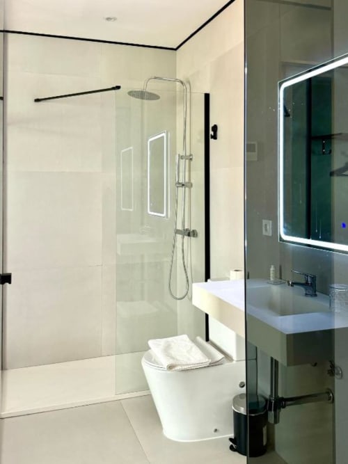 Cuarto de baño moderno en el ITOUR Hotel con ducha a ras de suelo, inodoro blanco y espejo iluminado en Museros