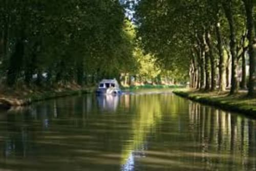 Canal paisible de Carcassonne bordé d'arbres majestueux et d'un bateau, reflet d'une voie navigable sereine