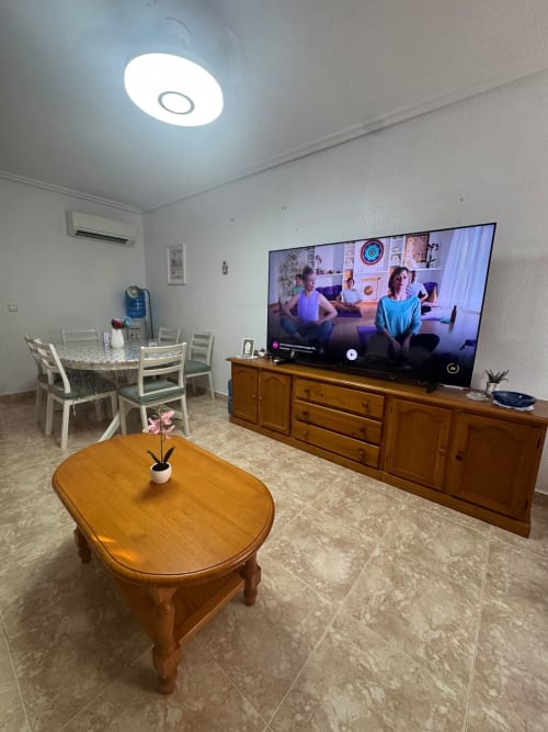Sala de estar moderna en cabaña Los Alcázares con TV, muebles de madera y luminosa lámpara LED de techo