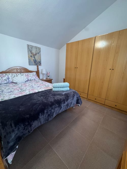 Dormitorio de la casita Haus Holiday Homes en Los Alcázares con cama de madera, ropa de cama floral y armario.