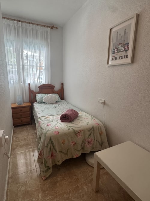 Acogedora habitación en la casa de vacaciones Haus Holiday Homes en Los Alcázares con cama individual, muebles de madera y póster de Nueva York