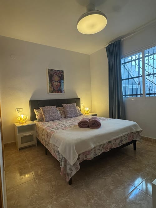 Dormitorio moderno con cama queen, iluminación amarilla y vistas al mar en Haus Holiday Homes, Los Alcázares