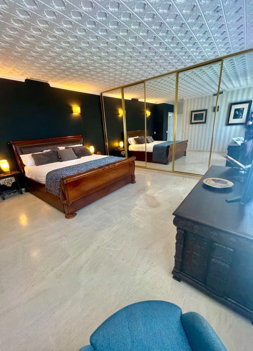 Dormitorio de lujo en Villa Magos Málaga con cama de madera, armario espejo, techo texturizado y mobiliario moderno
