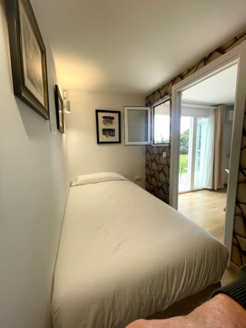 Dormitorio moderno en Villa Magos B&B en Málaga con cama blanca, vistas al jardín a través de puertas de cristal y decoración contemporánea.