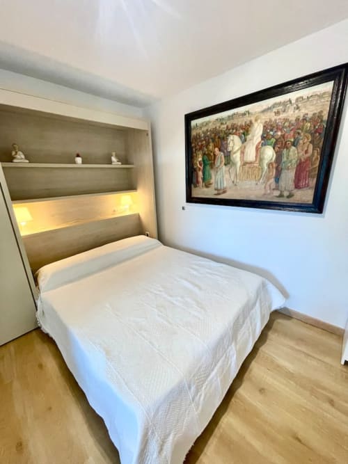Moderno dormitorio en Villa Magos con cama, cabecero integrado con iluminación, estanterías y obras de arte enmarcadas en Málaga