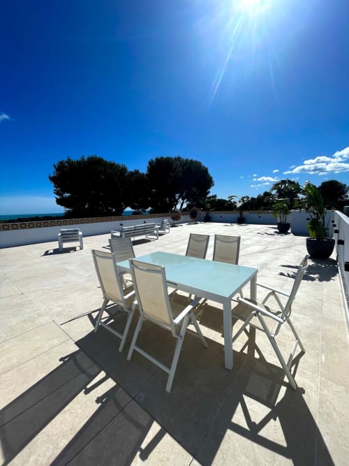 Terraza soleada de Villa Magos en Málaga con mesa de comedor, vistas al mar y árboles mediterráneos