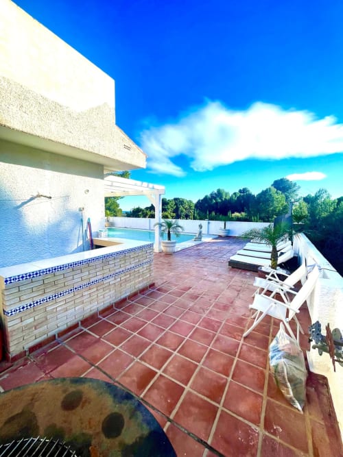 Terraza con piscina de Villa Magos, tumbonas y vistas al paisaje de Málaga bajo cielo azul