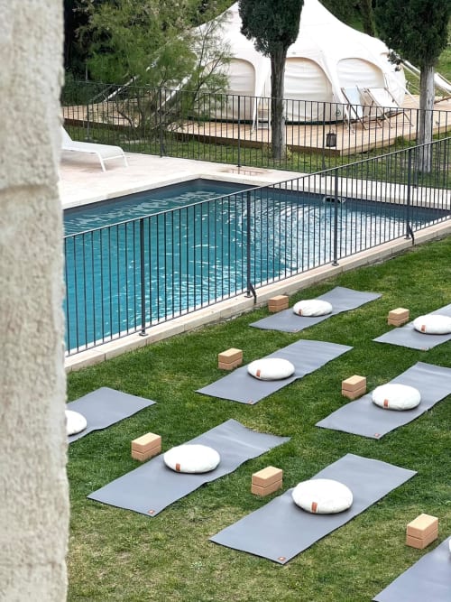 Outdoor yoga setup at Mas des Ecoliers with mats, cushions, pool and Mediterranean garden in Provence