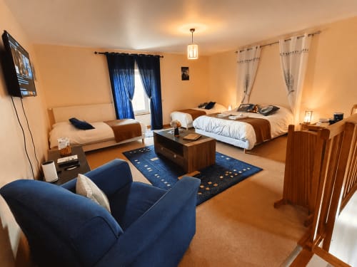 Studio de l'Écureuil à La Synchronicité B&B à Saint Sauveur Villages : chambre spacieuse avec deux lits, canapé bleu, mobilier en bois