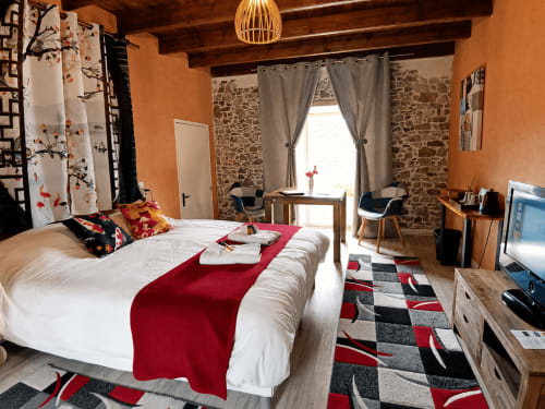 Chambre Sakura à La Synchronicité B&B : Chambre moderne aux murs terracotta, lit blanc, accents rouges, poutres bois et pierre