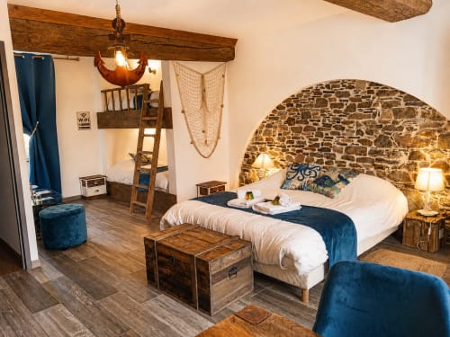 Chambre rustique à La Synchronicité B&B à Saint Sauveur avec poutres apparentes, voûte en pierre, lit blanc et accents en velours bleu