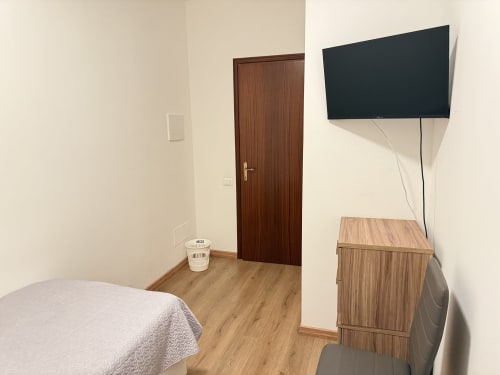 Camera da letto moderna dell'appartamento Ohana presso Le case di Clara con letto, mobili in legno, TV a parete e pavimentazione in legno