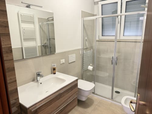 Bagno moderno nell'appartamento Ohana di Le case di Clara a Montecchio Maggiore, con lavandino, wc e doccia con box in vetro.