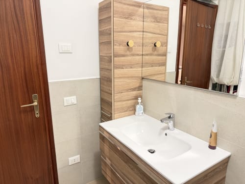 Bagno moderno presso l'appartamento Le case di Clara a Montecchio Maggiore con lavandino bianco, mobile in legno, specchio e design raffinato