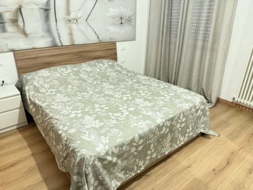 Spaziosa camera da letto nell'appartamento Ohana presso Le case di Clara con biancheria a motivi floreali, testiera in legno e ampie finestre