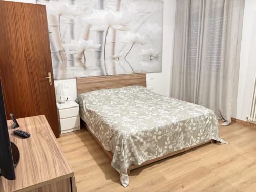 Camera moderna a Le case di Clara a Montecchio Maggiore con letto in legno, biancheria a motivi, scrivania e arte floreale bianca