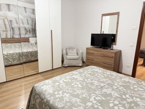Camera da letto a Le case di Clara, Montecchio Maggiore: letto con biancheria a fiori, cassettone in legno con TV e specchio, armadio