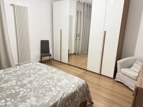 Camera Ohana presso Le case di Clara a Montecchio Maggiore con letto, armadio, sedia e pavimento in legno
