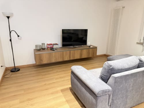 Salotto moderno con divano grigio, mobile TV in legno, TV schermo piatto e pavimenti in parquet nell'appartamento Ohana a Le case di