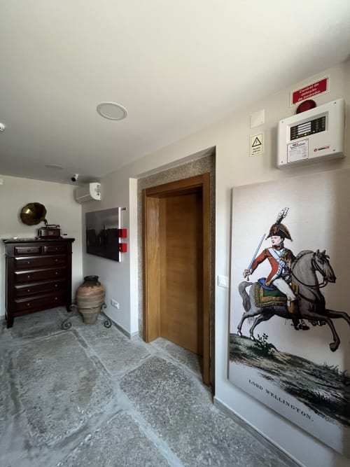 Wellington room hallway with historic military portrait, wooden door, dark furniture, stone flooring at RISOTURISMO