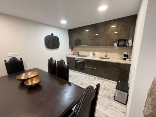 Modern kitchen and dining area in Quarto Wellington at RISOTURISMO with dark cabinetry, cream countertop, and black chairs
