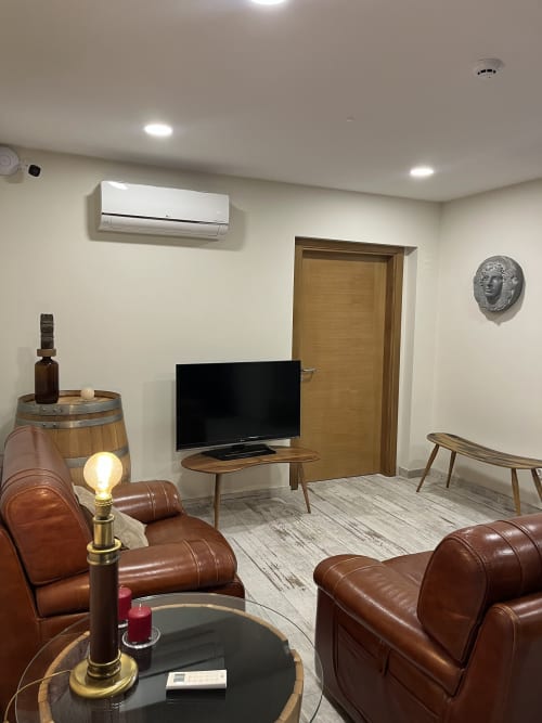 Quarto Wellington lounge with leather seating, flat-screen TV, wooden furnishings, and modern amenities at Quinta das Pias
