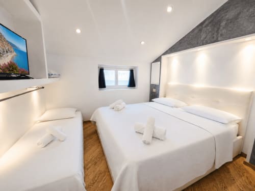 Modern bedroom at HomeholidaySanremo Luxe apartment in Sanremo with twin and double beds, white linens, wooden floor,