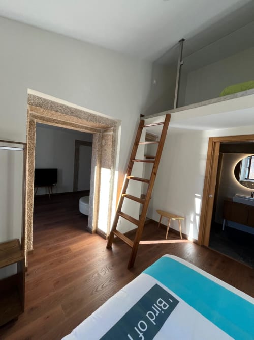 Quarto espaçoso da RISOTURISMO Quinta das Pias com escada de madeira, piso em madeira escura e acesso a salas contíguas