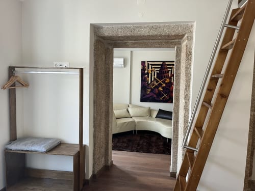Quarto Junot na Quinta das Pias: suíte moderna com sofá curvo creme, escada de madeira e entrada com arco de pedra