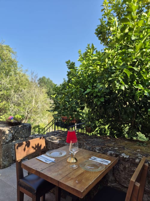 Conjunto de comedor exterior en Aldea Rural Pazos De Arenteiro con árboles verdes y cielo despejado de fondo