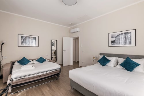 Camera da letto spaziosa e moderna nella casa vacanze Flavia a Roma con due letti, cuscini teal e opere d'arte contemporanea