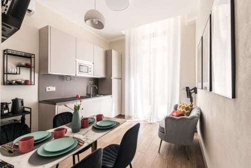 Moderna cucina e zona living con tavolo da pranzo, mobili bianchi e spazio abitativo in Flavia's Holiday Home a Roma