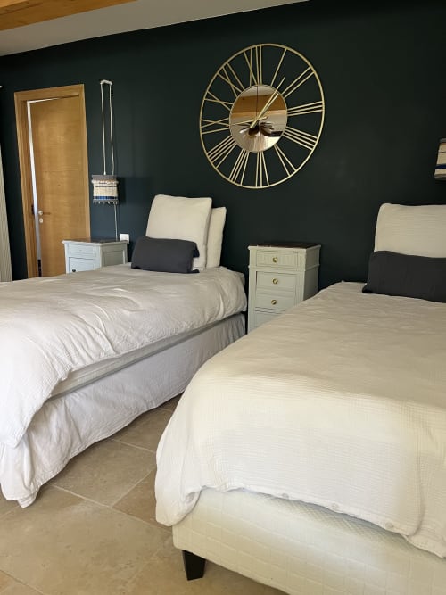 Modern double bedroom with dark accent wall, twin beds with cream bedding, gold sunburst clock, Mas des Ecoliers,