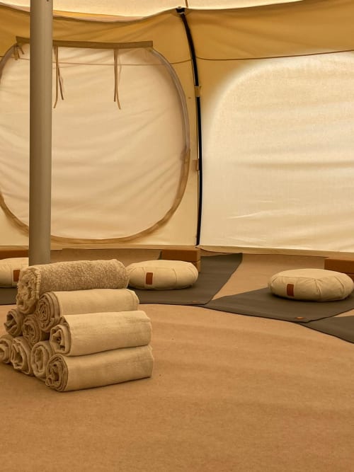 Glamping tent interior at Mas des Ecoliers Provence with rolled blankets, cushions, and canvas walls